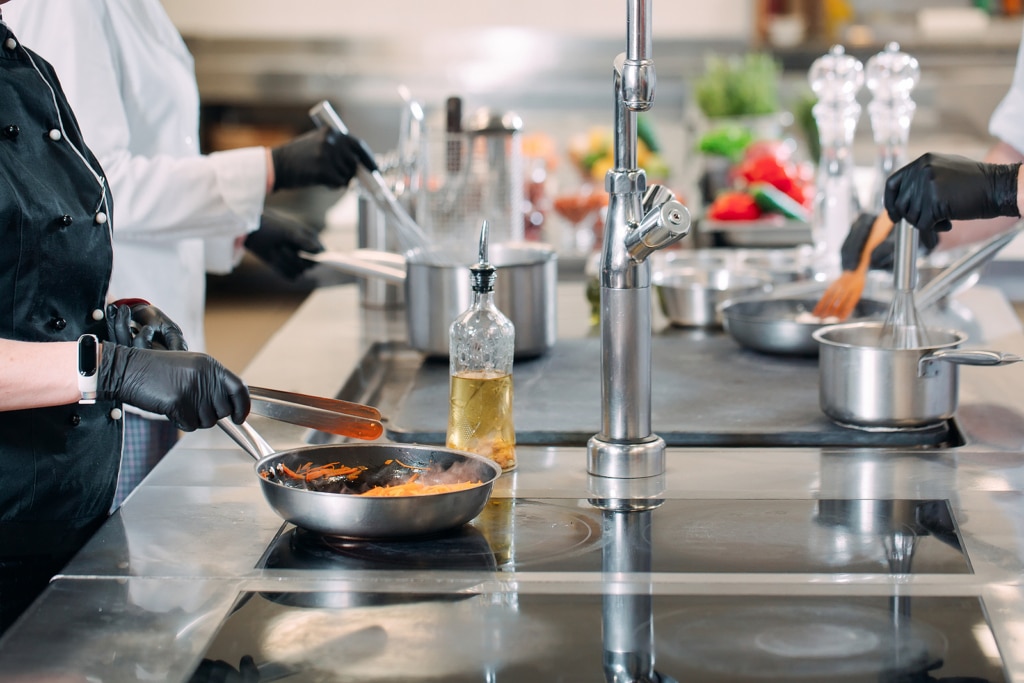 Cooks Prepare Meals On An Electric Stove In A Professional Kitch